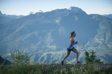 Seitenansicht einer sportlichen Frau beim Joggen auf einem Bergpfad - FSIF01387