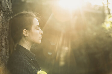 Side view of young woman with eyes closed enjoying sunlight at park - FSIF01388