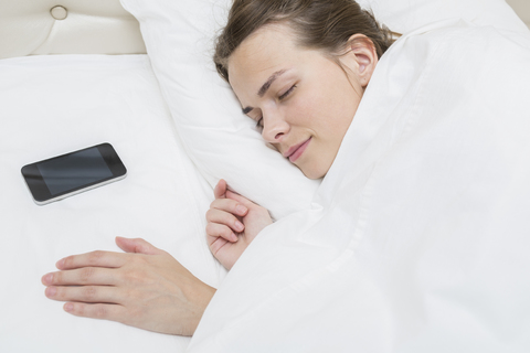 Hohe Winkel Ansicht der schönen Frau schlafen mit Smartphone auf Kissen im Bett, lizenzfreies Stockfoto