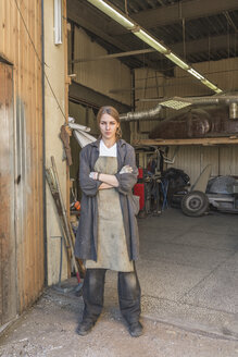 Porträt eines selbstbewussten weiblichen Mechanikers, der mit verschränkten Armen in einer Werkstatt steht - FSIF01413