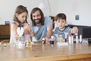 Vater und Kinder machen ein wissenschaftliches Experiment am Tisch im Haus - FSIF01435