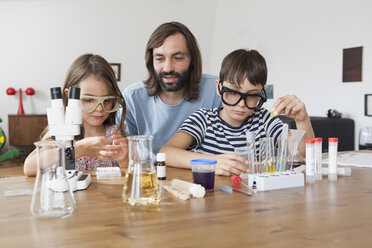 Father assisting children in doing school science project at home - FSIF01441