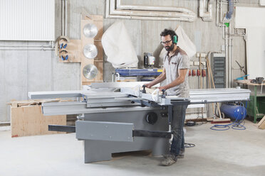 Full length of carpenter using a sliding table saw in workshop - FSIF01442