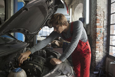 Mechaniker, der in einer Autowerkstatt den Motor eines Autos untersucht - FSIF01471