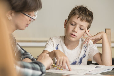 Grandmother teaching grandson on table at home - FSIF01490