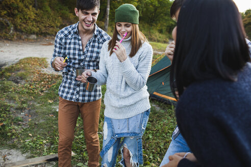 Happy friends brushing teeth at campsite - FSIF01505