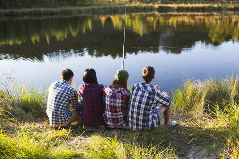 Rear view of friends fishing at lakeshore - FSIF01519