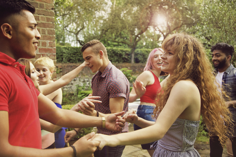 Fröhliche Freunde tanzen auf dem Hof während einer Party, lizenzfreies Stockfoto