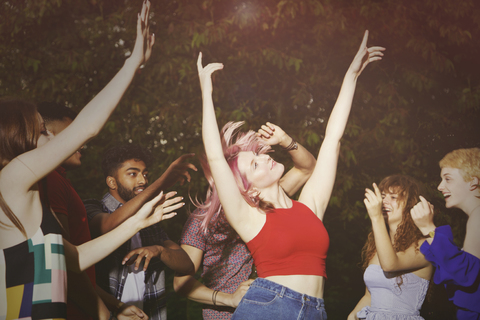 Excited woman dancing with friends at yard during party stock photo