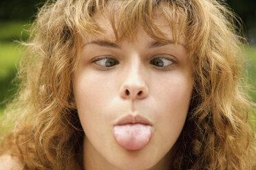 Close-up of cross-eyed woman sticking out tongue - FSIF01543