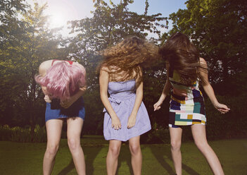 Aufgeregte Freundinnen, die sich an einem sonnigen Tag im Garten die Haare zuwerfen - FSIF01547