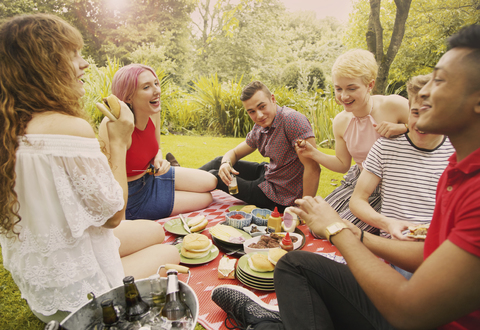 Fröhliche Freunde beim Essen auf einer Party im Hof, lizenzfreies Stockfoto