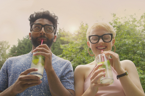 Niedriger Winkel Blick auf fröhliche Paar trinken Limonade im Hof, lizenzfreies Stockfoto