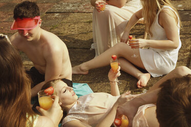 Hochformatige Ansicht von Freunden mit Getränken in der Hand beim Entspannen am Pool - FSIF01574