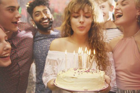 Frau bläst Kerzen aus, während sie mit Freunden Geburtstag feiert - FSIF01578