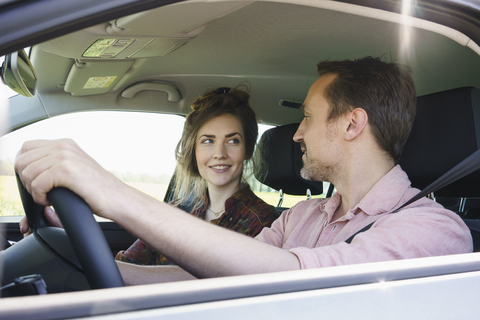 Lächelndes Paar, das sich während der Fahrt im Auto ansieht, lizenzfreies Stockfoto