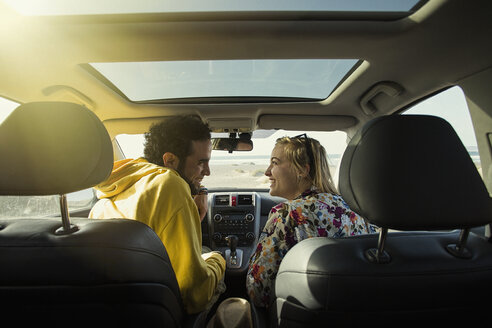 Rückansicht eines glücklichen Paares, das sich im Auto ansieht - FSIF01598