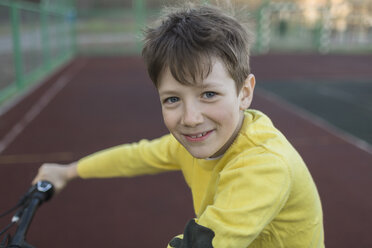 Porträt eines lächelnden Jungen beim Radfahren im Gericht - FSIF01635