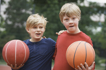 Brüder, die im Park die Arme umeinander legen und Basketbälle halten - FSIF01645