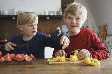Portrait of disabled boy sitting with brother at table with vegetables in kitchen - FSIF01651