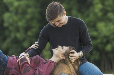 Glückliche Frau auf dem Schoß ihres Freundes im Park liegend - FSIF01654