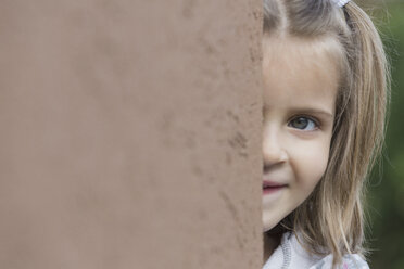 Portrait of cute girl standing behind wall - FSIF01657