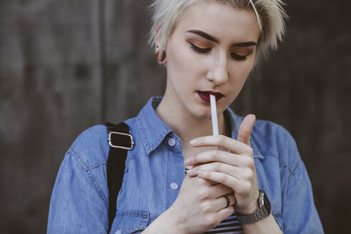 Young fashionable woman smoking cigarette while standing outdoors - FSIF01674