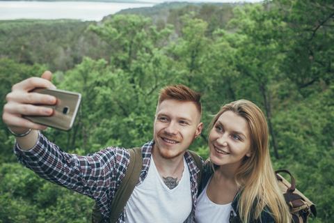 Lächelndes Paar nimmt Selfie durch Smartphone im Wald, lizenzfreies Stockfoto