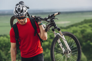 Mountainbiker trägt Fahrrad bergauf - FSIF01719