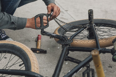 Detailaufnahme eines Teenagers, der eine Fahrradkette repariert - FSIF01730