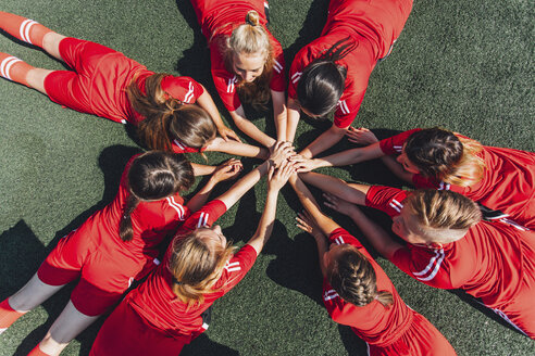 High angle view of sports team stacking hands on field - FSIF01744
