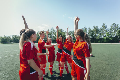 Excited soccer players with hands raised standing on field - FSIF01745