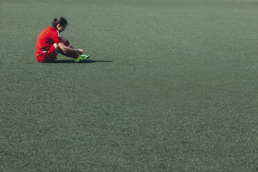 Seitenansicht eines Fußballspielers, der auf dem Spielfeld sitzt - FSIF01748