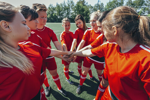 Close-up of sports team stacking hands on field - FSIF01754