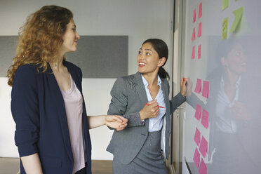 Business people discussing over adhesive notes at creative office - FSIF01799