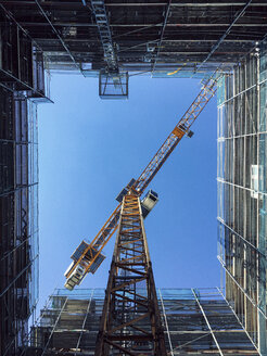 Unmittelbar unter der Aufnahme eines Krans inmitten eines Glasgebäudes vor einem strahlend blauen Himmel - FSIF01802