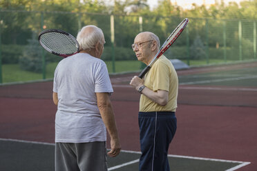 Ältere Freunde tragen Tennisschläger und unterhalten sich auf dem Spielfeld - FSIF01832