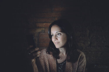 Portrait of woman using smartphone at home in the dark - GEMF01887