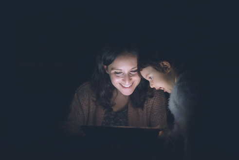 Mutter und Tochter benutzen ein digitales Tablet zu Hause im Dunkeln - GEMF01891