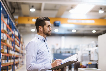 Businessman in factory holding folder - DIGF03384