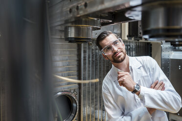 Man wearing lab coat and safety goggles at machine - DIGF03392