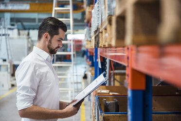 Man in factory storehouse holding folder - DIGF03394