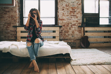 Frau in voller Länge beim Fotografieren durch eine Spiegelreflexkamera im Schlafzimmer zu Hause - FSIF01842