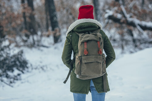 Rückansicht einer jungen Frau mit Rucksack auf einem schneebedeckten Feld - FSIF01858