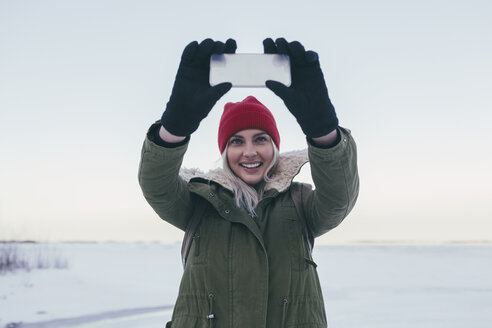 Junge Frau macht im Winter ein Selfie mit ihrem Smartphone - FSIF01861