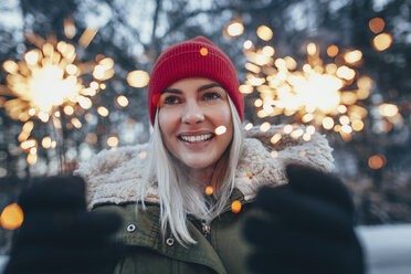 Glückliche Frau mit Wunderkerzen im Winter - FSIF01864