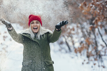 Porträt einer glücklichen jungen Frau, die im Schnee spielt - FSIF01866