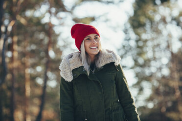 Low angle view of happy young woman wearing knit hat and jacket while looking away - FSIF01870