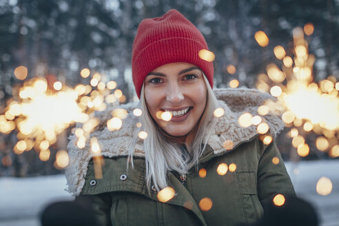 Porträt einer lächelnden Frau mit Wunderkerzen im Winter - FSIF01874
