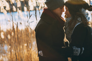 Young couple embracing while standing on field during winter - FSIF01875
